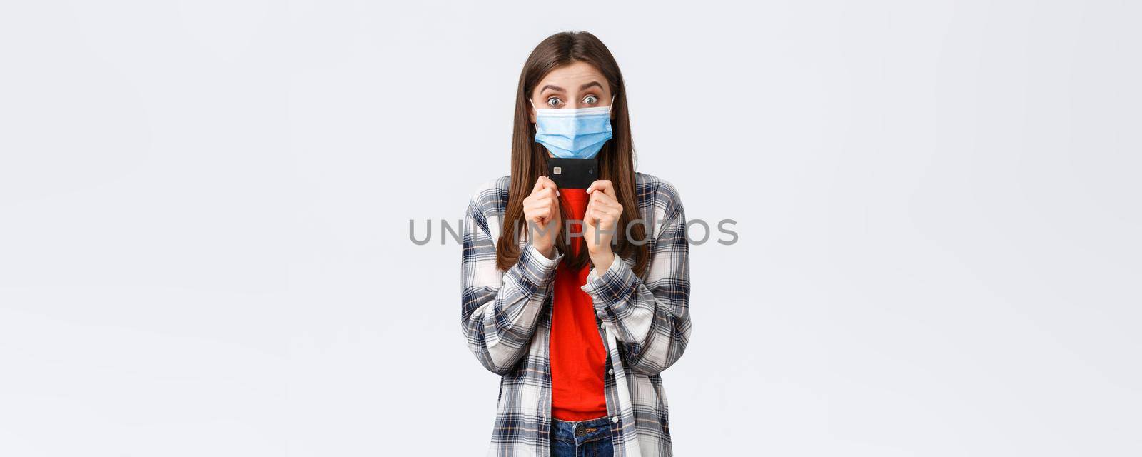 Coronavirus outbreak, working from home, online shopping and contactless payment concept. Rejoicing, happy pretty woman in medical mask showing credit card, smiling white background.
