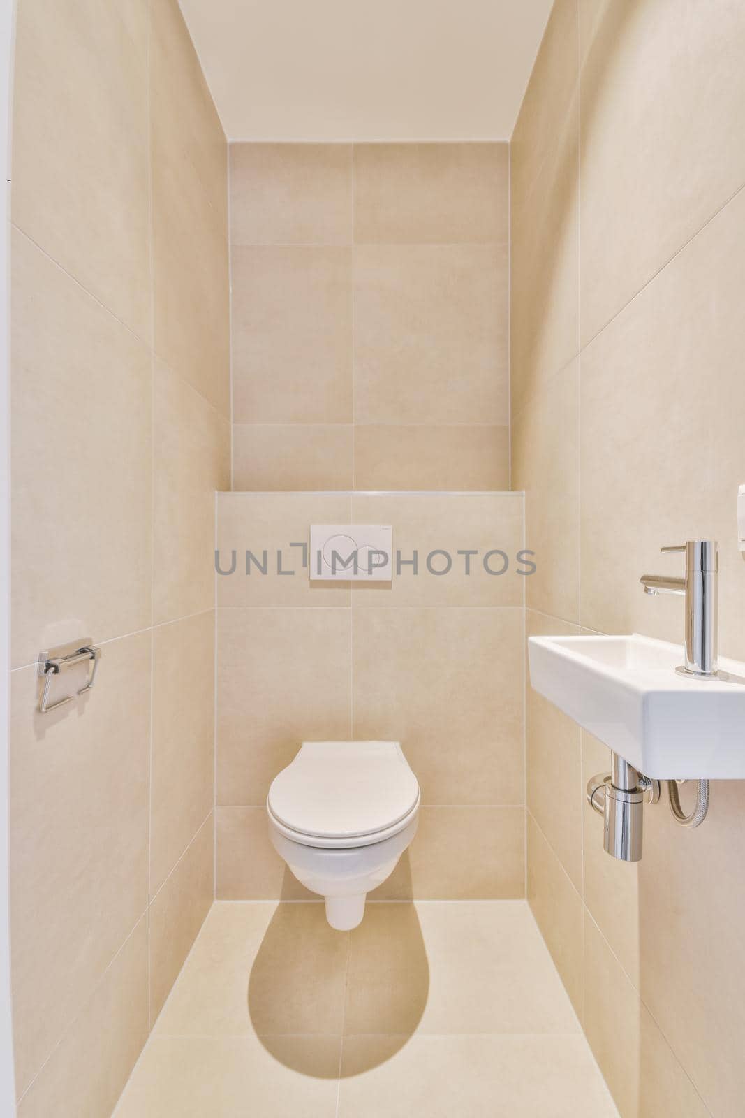 Modern flush toilet and ceramic sink installed on white tiled walls near mirror and towel in small restroom at home