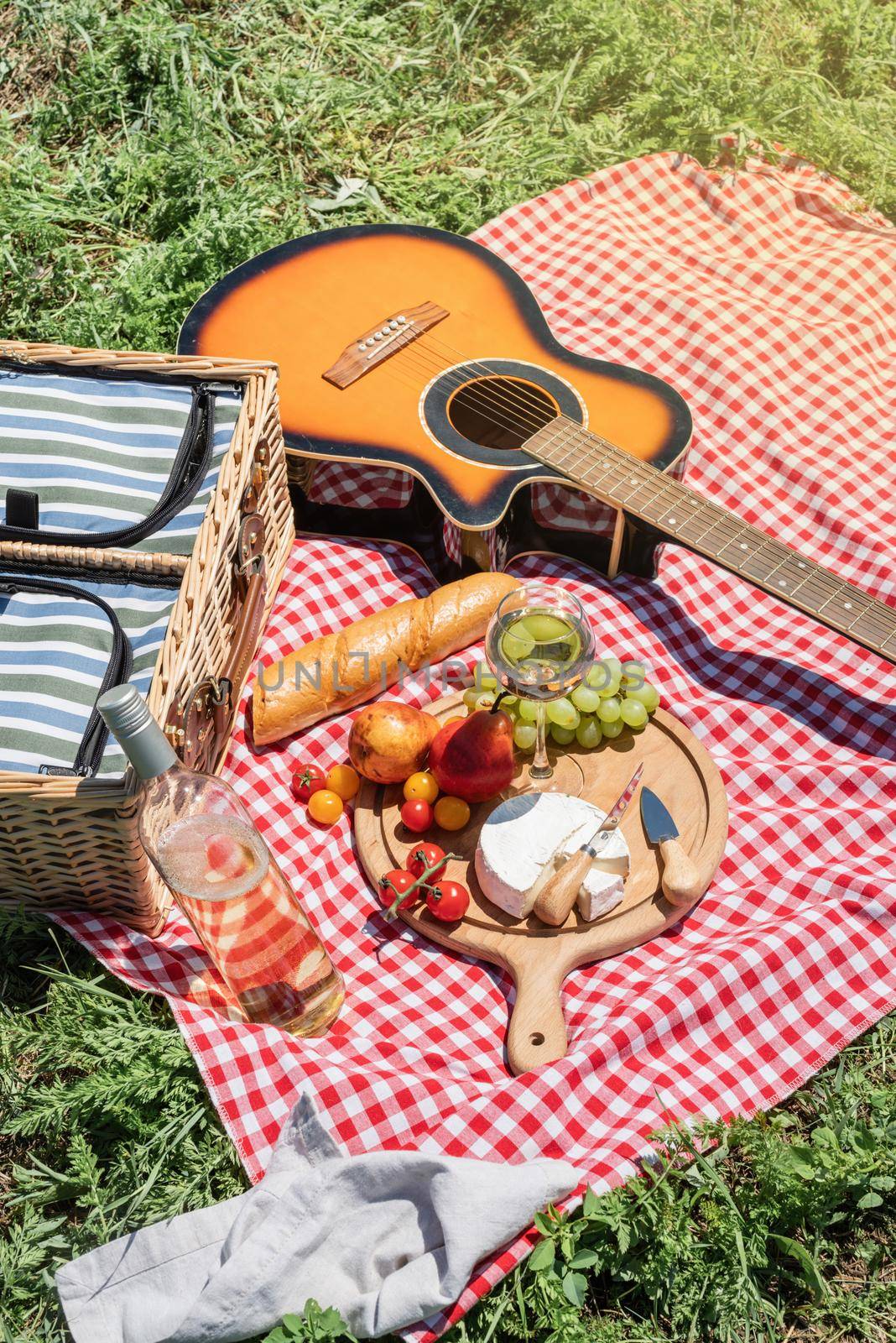 Closeup of picnic basket with drinks and food on the grass by Desperada