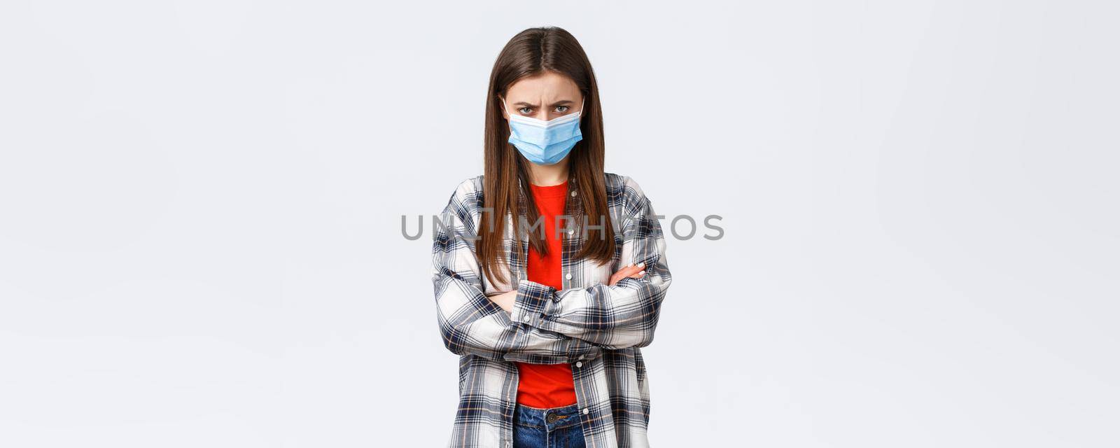 Coronavirus outbreak, leisure on quarantine, social distancing and emotions concept. Angry young mad girlfriend in medical mask and checked casual shirt, feel offended, sulking and stand defensive.