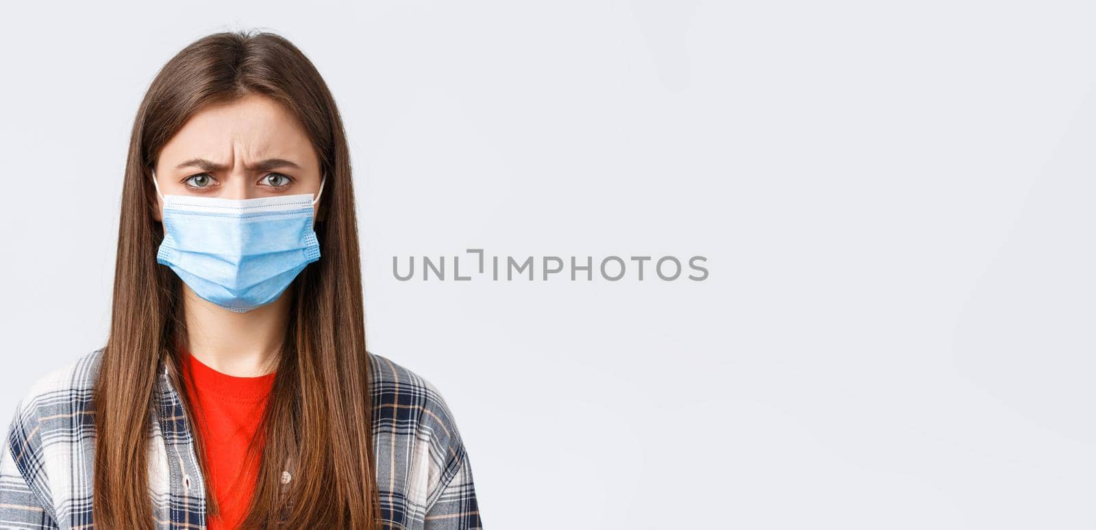 Coronavirus outbreak, leisure on quarantine, social distancing and emotions concept. Close-up of bothered or displeased woman in medical mask, condemn someone, frowning upset by Benzoix