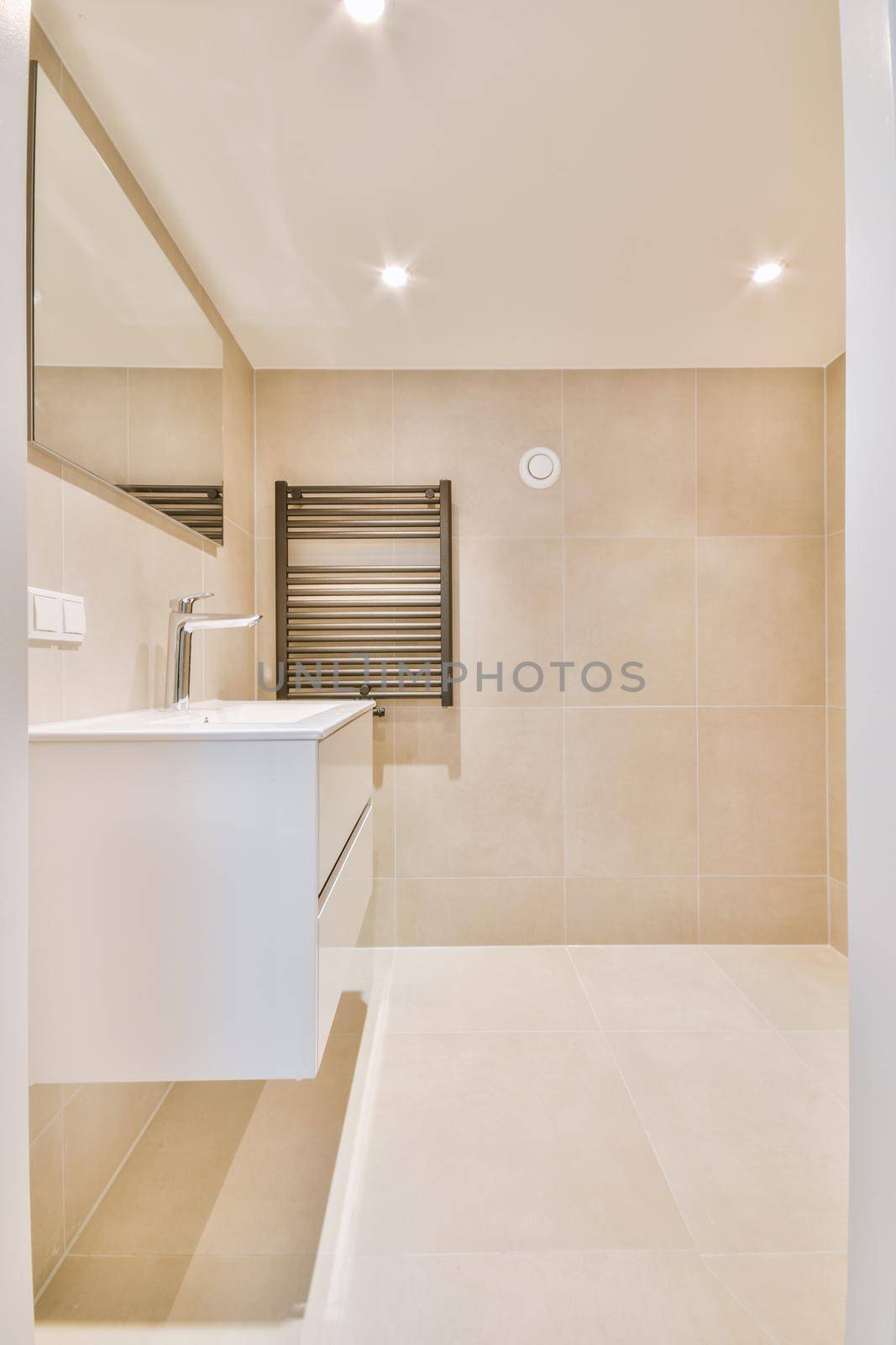 Shiny faucet installed on clean sink near mirror in modern bathroom at home