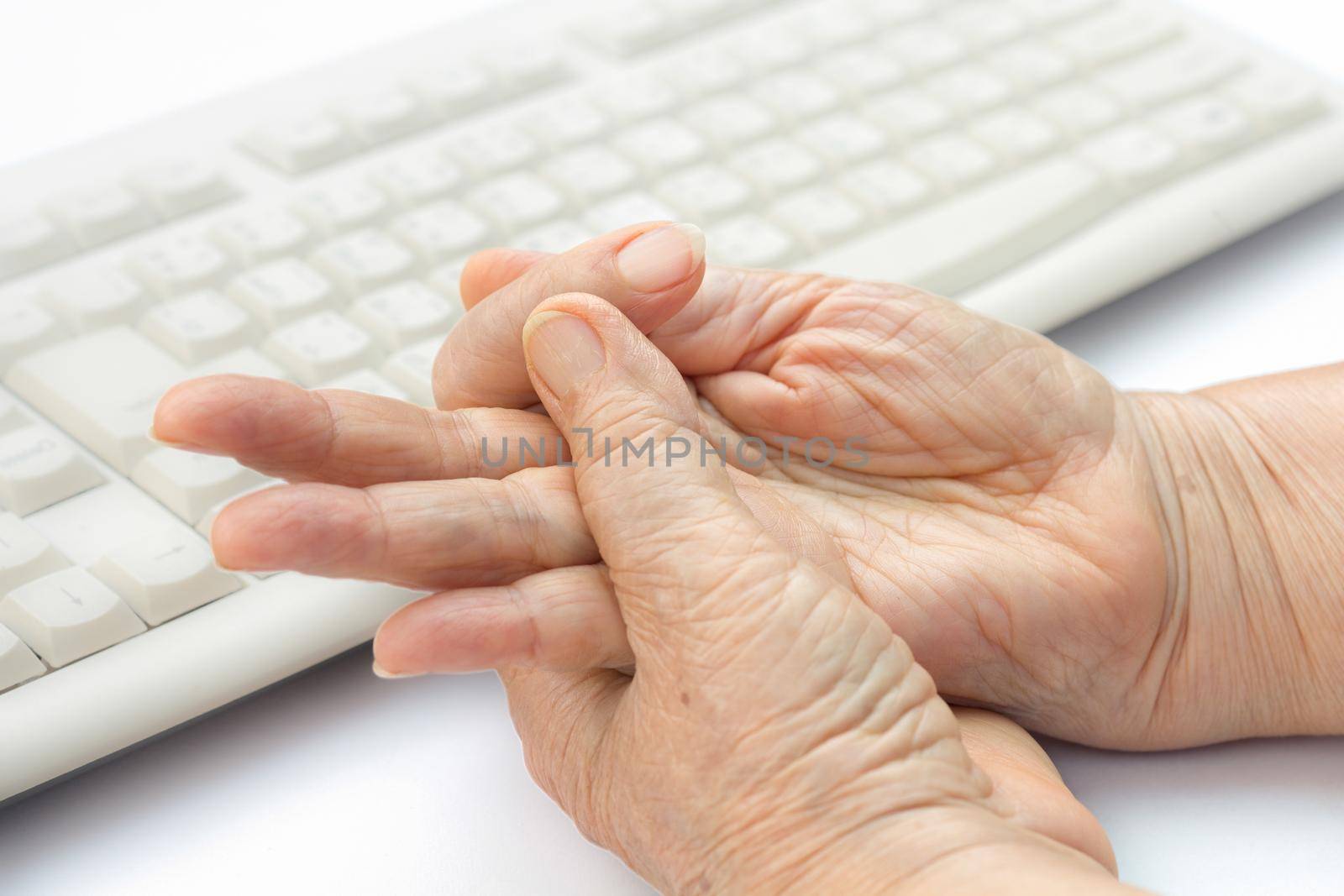 Senior woman painful finger due to prolonged use of keyboard and mouse.