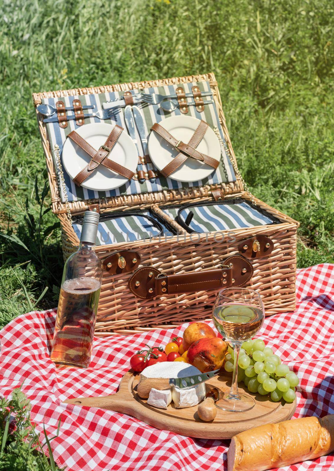 Closeup of picnic basket with drinks and food on the grass. Nice picnic on sunny summer day, fun and leisure