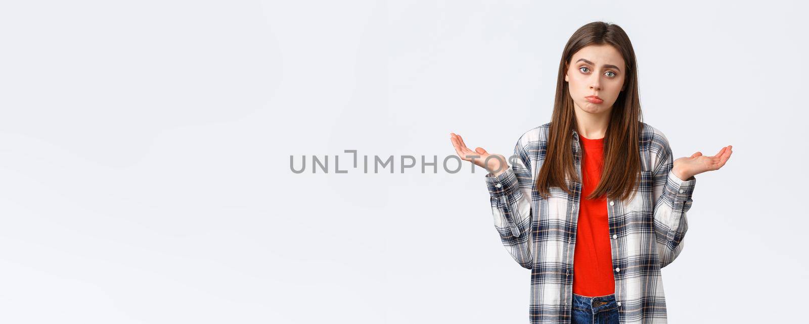 Lifestyle, different emotions, leisure activities concept. Reluctant and careless young woman shrugging with hands spread sideways, dont know, cant help, have no idea, stand white background.