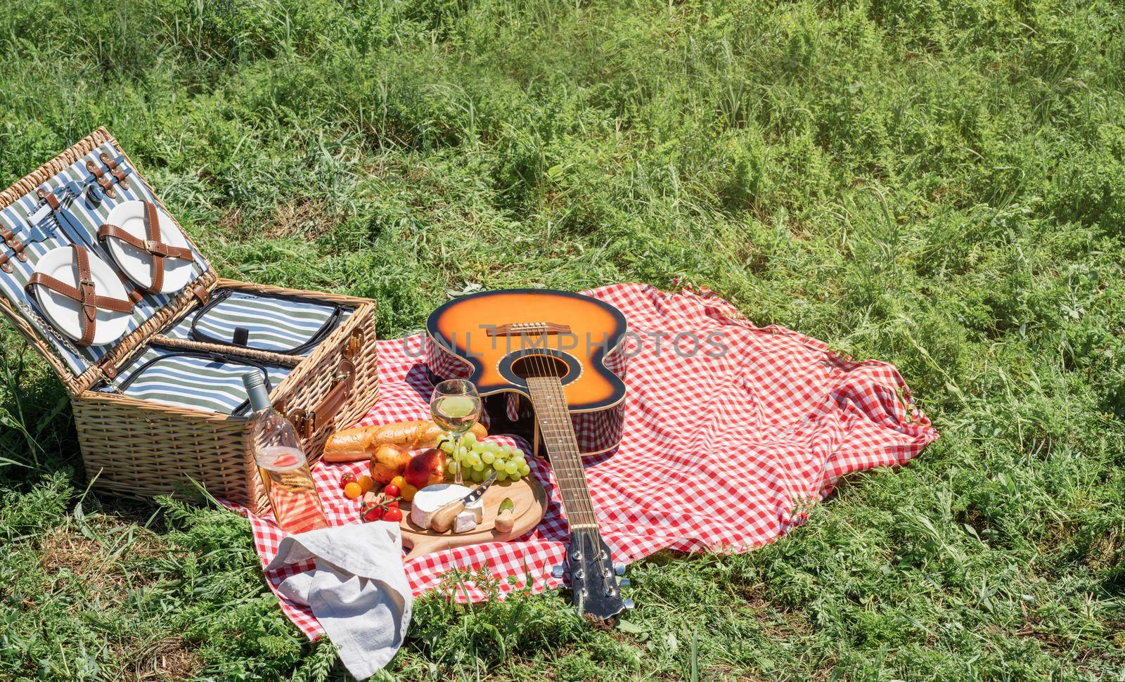 Closeup of picnic basket with drinks and food on the grass by Desperada