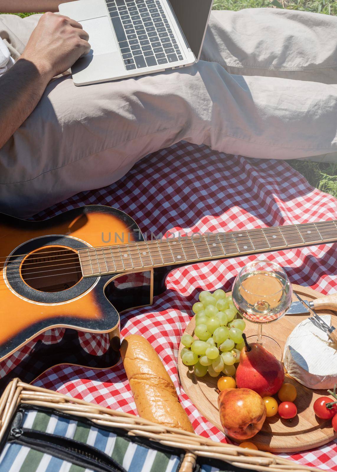 unrecognizable man in white pants outside having picnic and using laptop, working outdoors. summer leisure and fun