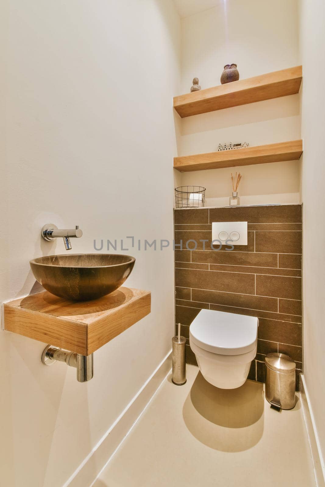 Modern flush toilet and ceramic sink installed on white tiled walls near mirror and towel in small restroom at home