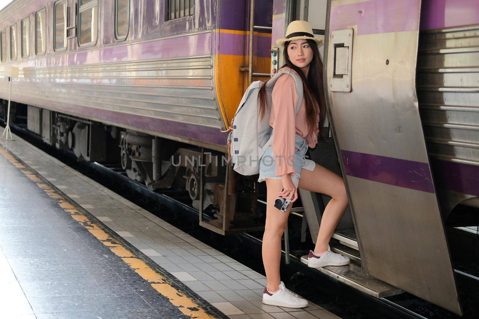 young woman tourist traveler stepping up to train on railway at train station. Travel journey trip concept