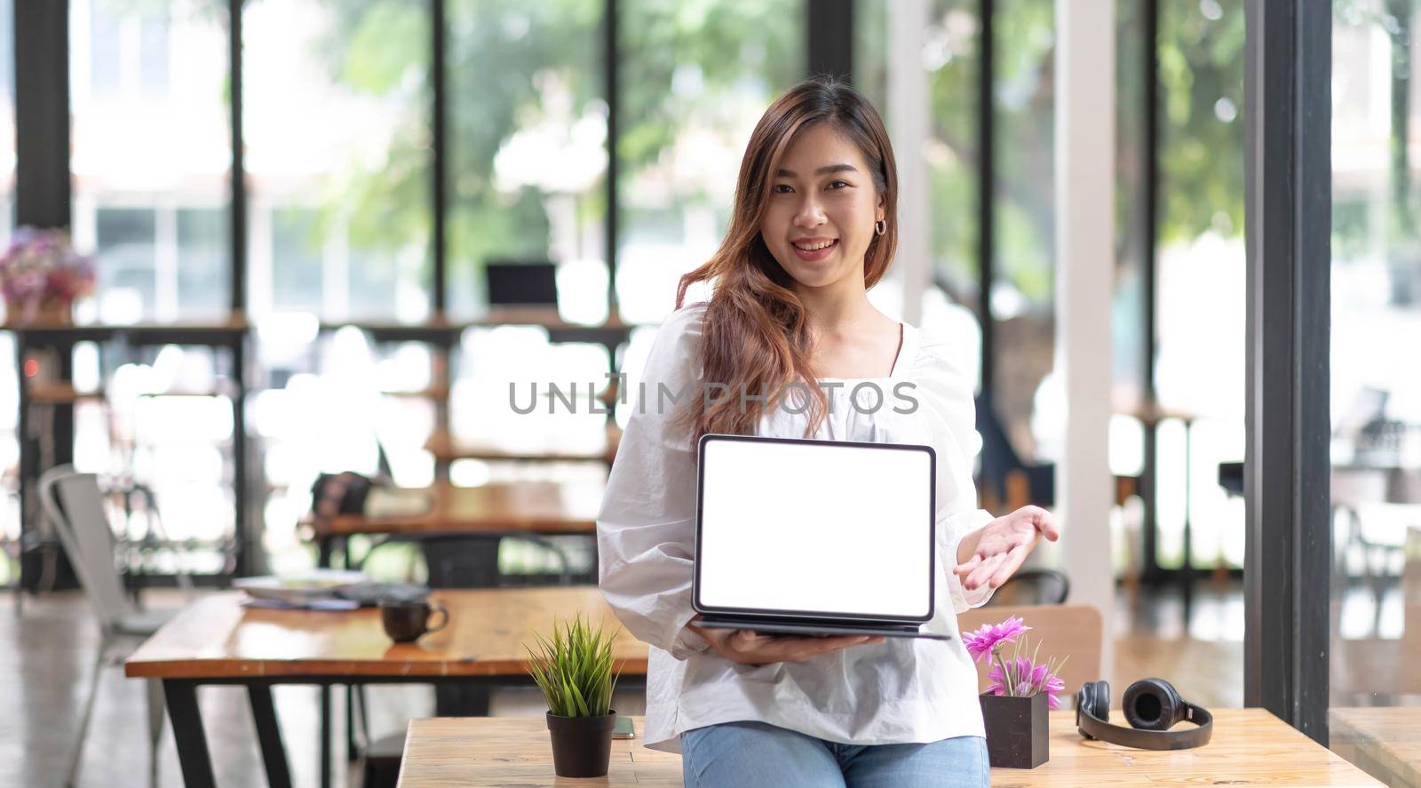 Portrait of Asian young businesses owners showing tablet with blank screen at office..