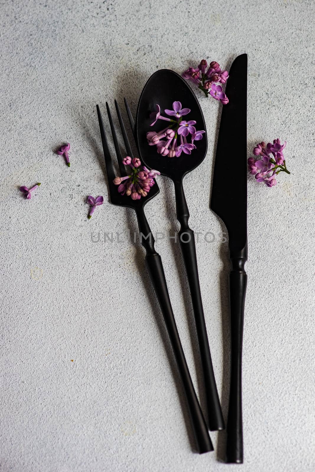 Minimalistic cutlery set with spring lilac flower blossom on concrete background