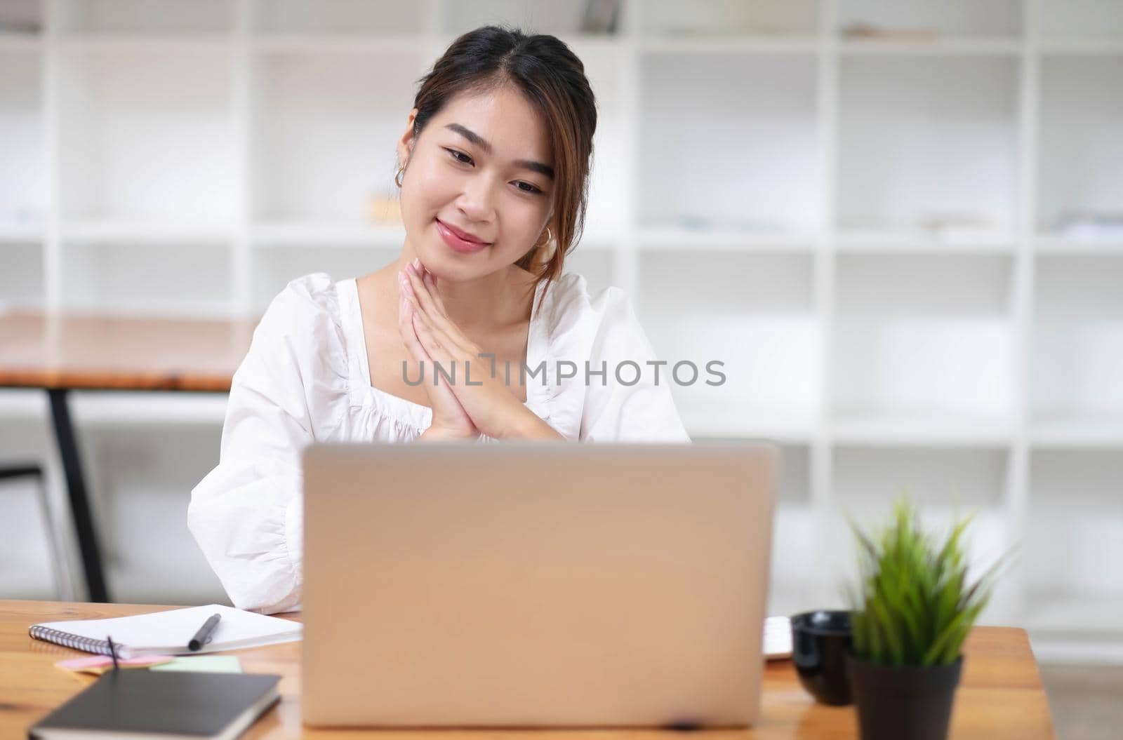 Happy young asian businesswoman sitting on her workplace in the office. Young woman working at laptop in the office. by wichayada