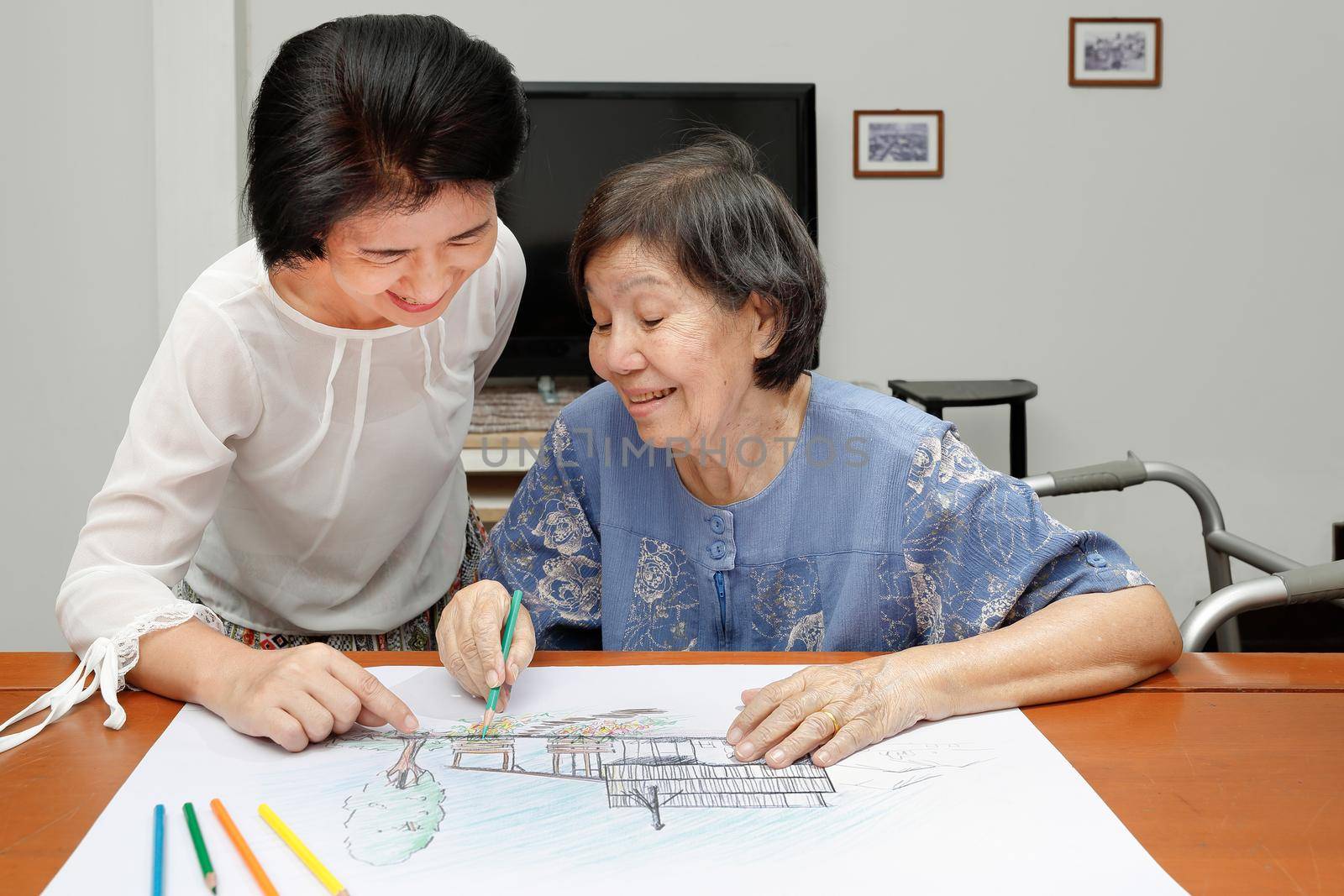Elderly woman painting color on her drawing with daughter , hobby at home by toa55