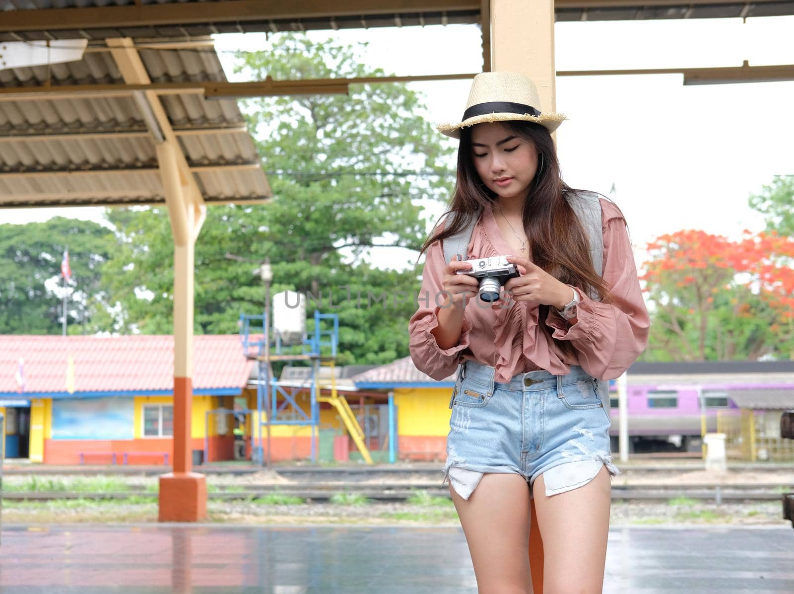 woman traveler holding camera taking photo at train station. travel trip journey concept
