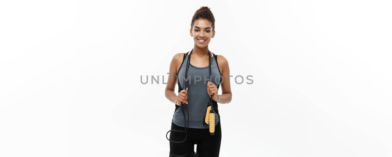 Sport, training, lifestyle and Fitness concept - portrait of beautiful happy African American woman exercising with jumping rope. Isolated on white studio background