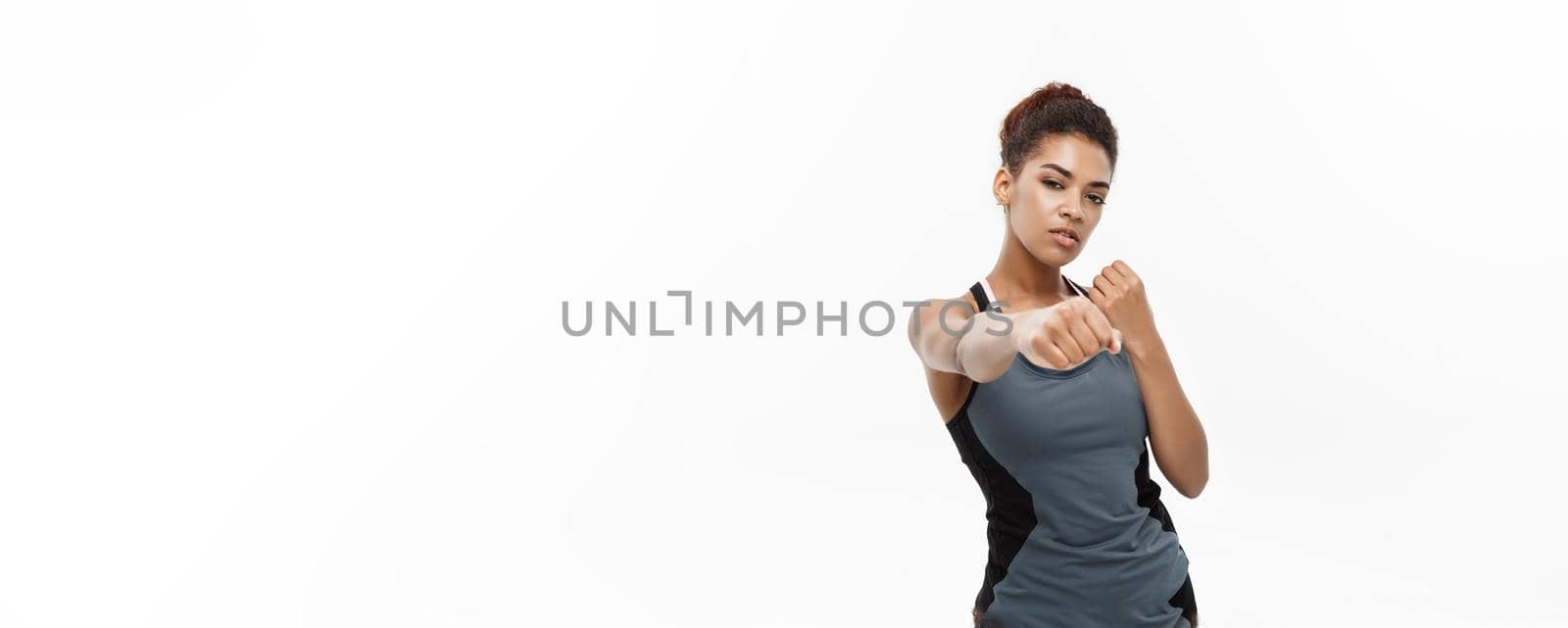 Healthy and Fitness concept - portrait of African American woman punching in air with confident face. Isolated on white background