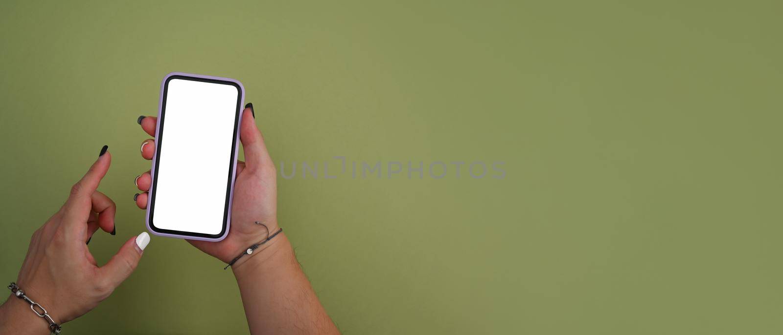 Mockup image of woman hand holding smart phone on green background with copy space. by prathanchorruangsak