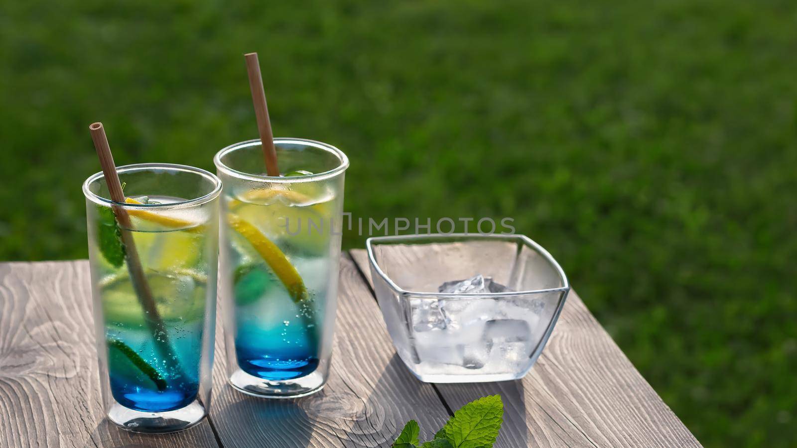 Two glasses with summer cool blue lagoon cocktail on a wooden table. Selective focus by galsand