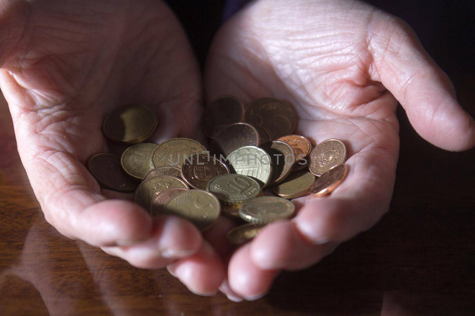 Wrinkled hands of elderly woman counting coins. Close up.