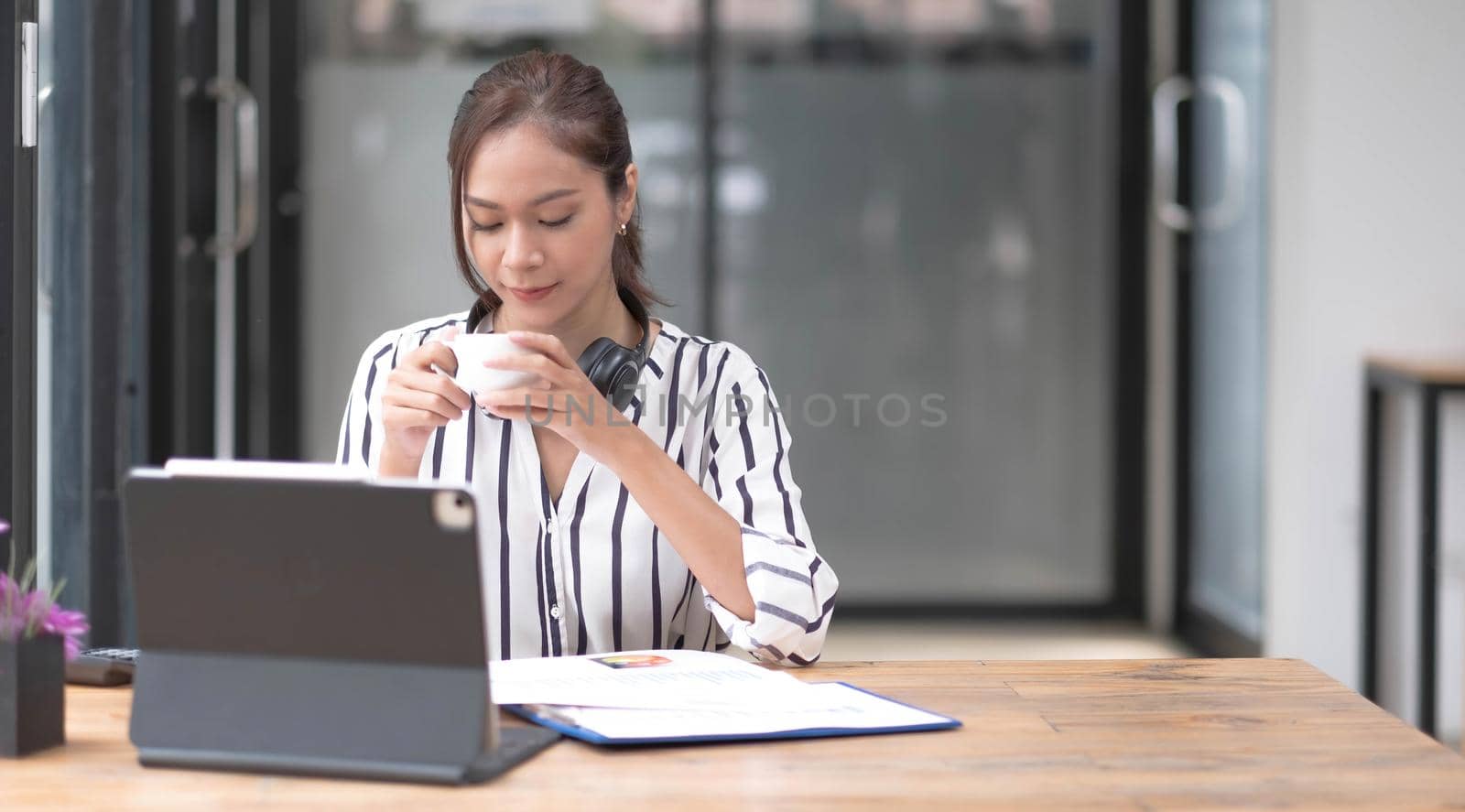 Image of a young woman smiling through a laptop's web camera while holding a cup of coffee in the kitchen at home..