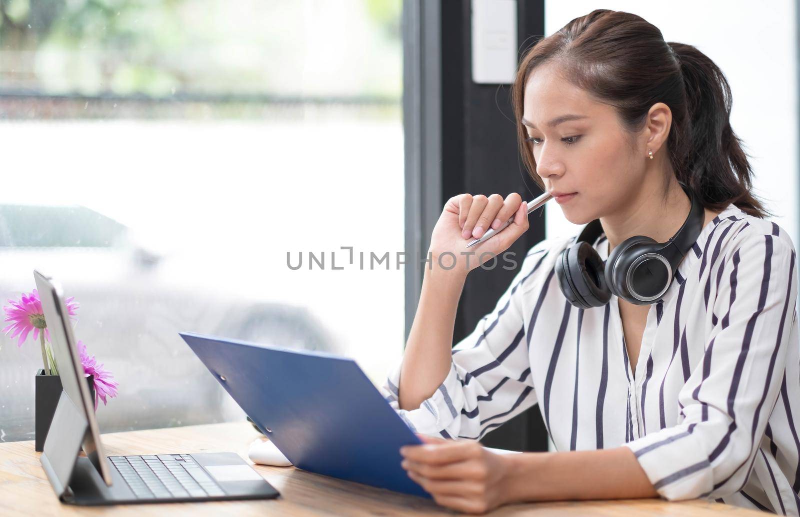 asian woman young wearing headset, communicating with client via video computer call. by wichayada