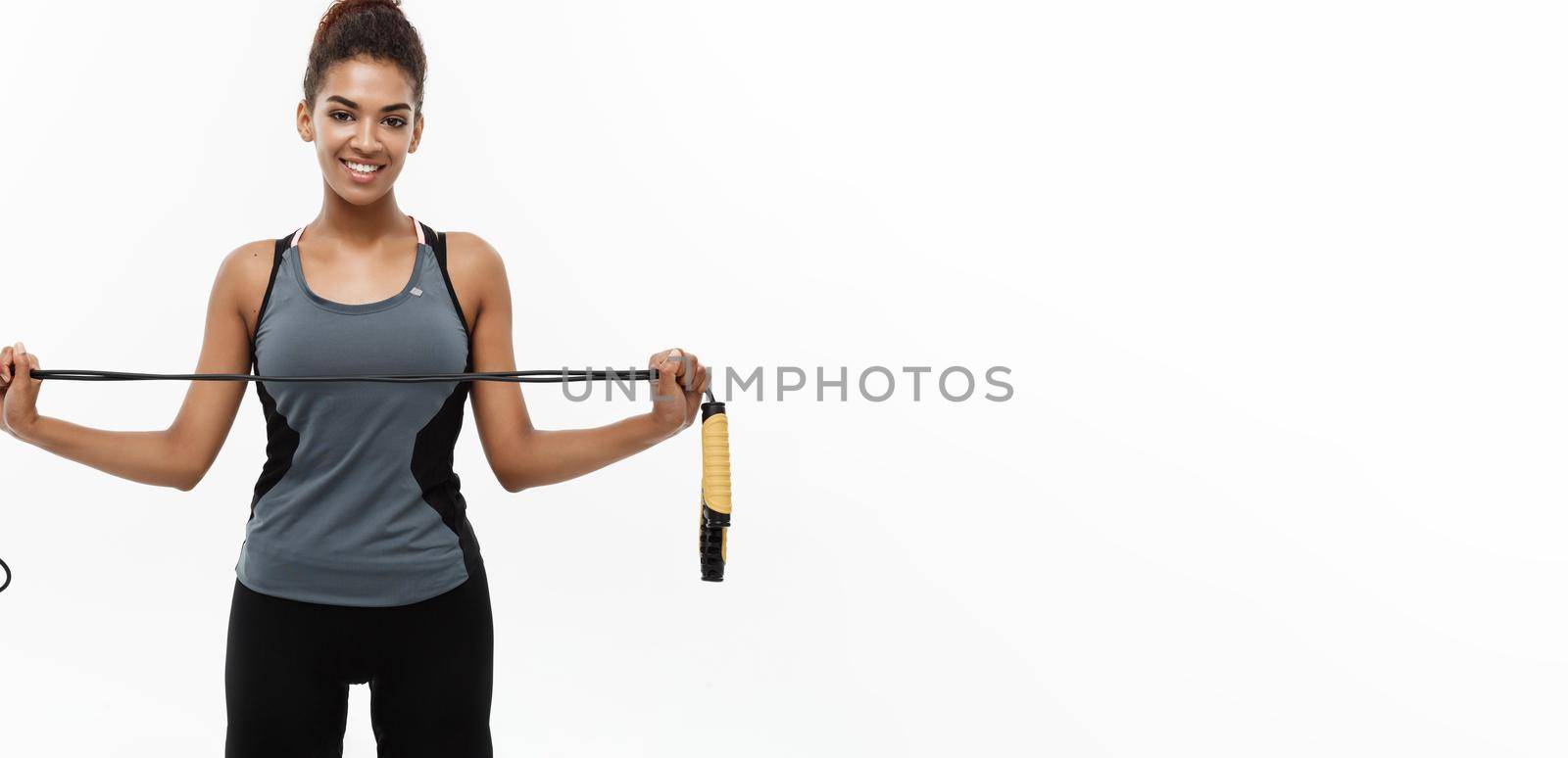 Sport, training, lifestyle and Fitness concept - portrait of beautiful happy African American woman exercising with jumping rope. Isolated on white studio background. by Benzoix