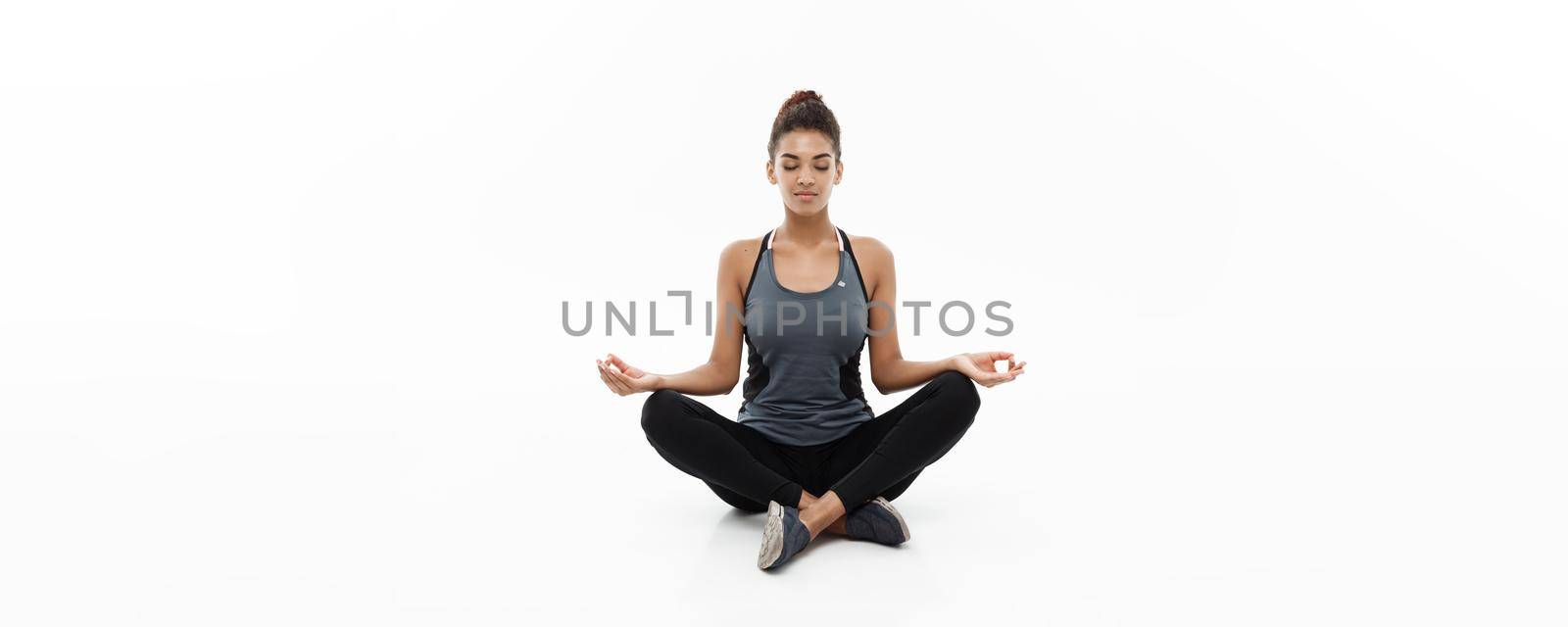 Healthy and Fitness concept - Beautiful American African lady in fitness clothing doing yoga and meditation. Isolated on white background