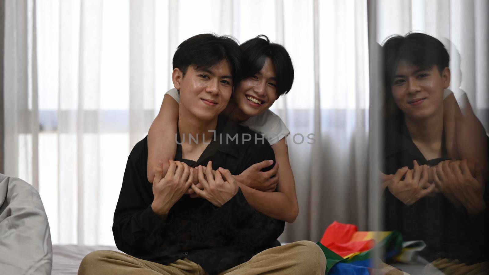 Happy same sex male couple hugging each other and smiling at camera. LGBT, pride, relationships and equality concept by prathanchorruangsak