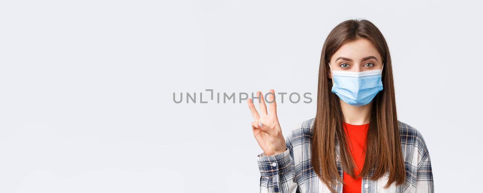 Coronavirus outbreak, leisure on quarantine, social distancing and emotions concept. Close-up of cheerful attractive woman in medical mask show number three, third, white background by Benzoix