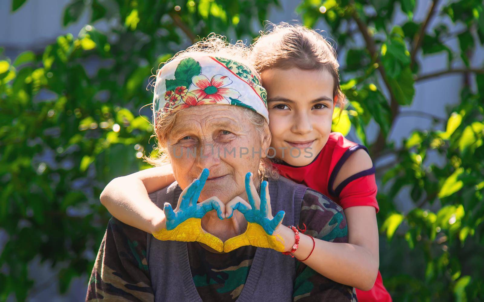 Child and grandmother hand drawn flag of Ukraine. Selective focus. by yanadjana