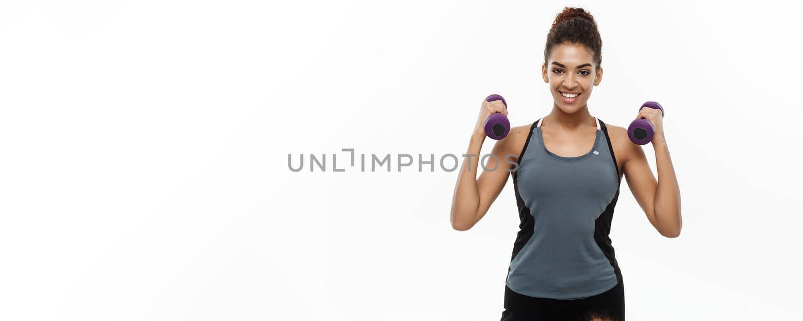 Healthy and Fitness concept - Beautiful American African lady in fitness clothes workout with dumbbell. Isolated on white background. by Benzoix