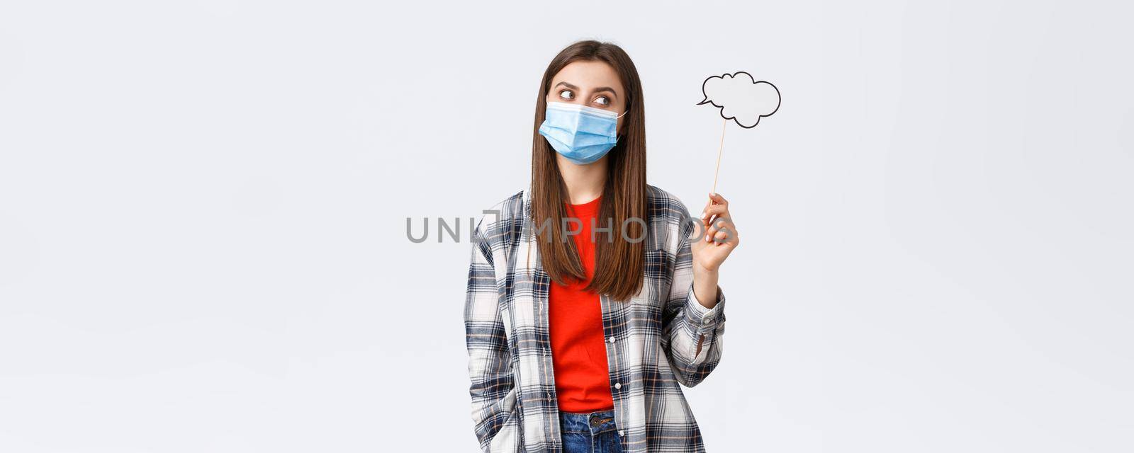 Coronavirus outbreak, leisure on quarantine, social distancing and emotions concept. Thoughtful smart young girl in medical mask searching for inspiration, thinking, holding commend cloud.