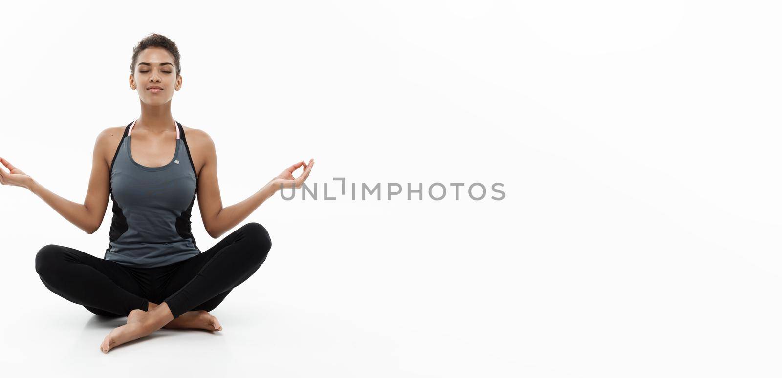 Healthy and Fitness concept - Beautiful American African lady in fitness clothing doing yoga and meditation. Isolated on white background. by Benzoix