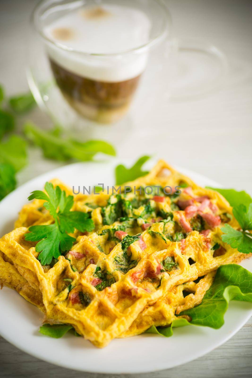 Egg omelet stuffed with greens and sausage fried in the form of waffles, on a wooden table