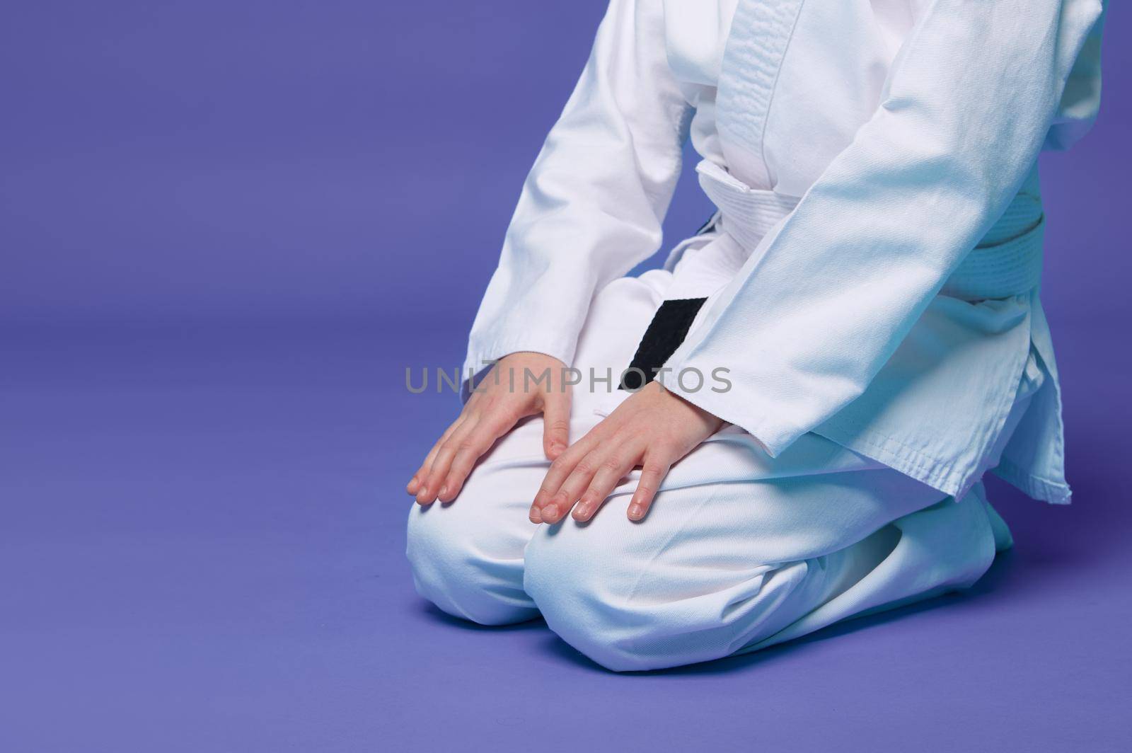 Cropped view of an aikido fighter in a white kimono during the practice of oriental martial arts, isolated over purple background with copy space for advertising text