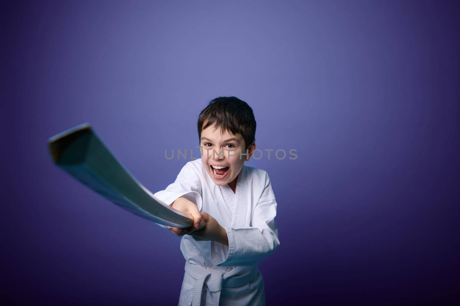 Portrait of a confident strong European teenage boy aikido fighter wearing traditional samurai hakama kimono learning fight with bamboo sword katana. Aikido Learning and Oriental martial arts Concept