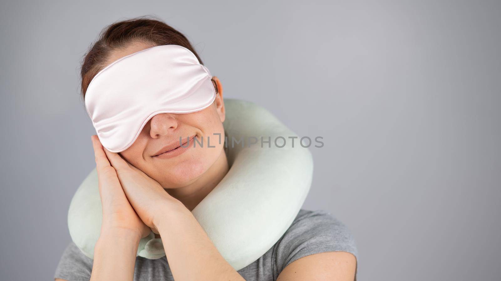 Smiling caucasian woman with travel pillow and sleeping mask isolated on white background