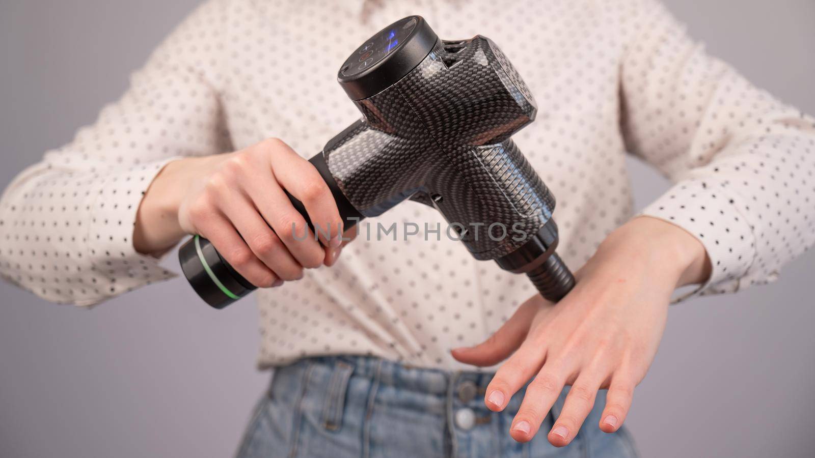 Caucasian business woman massaging her wrist with a percussion massager