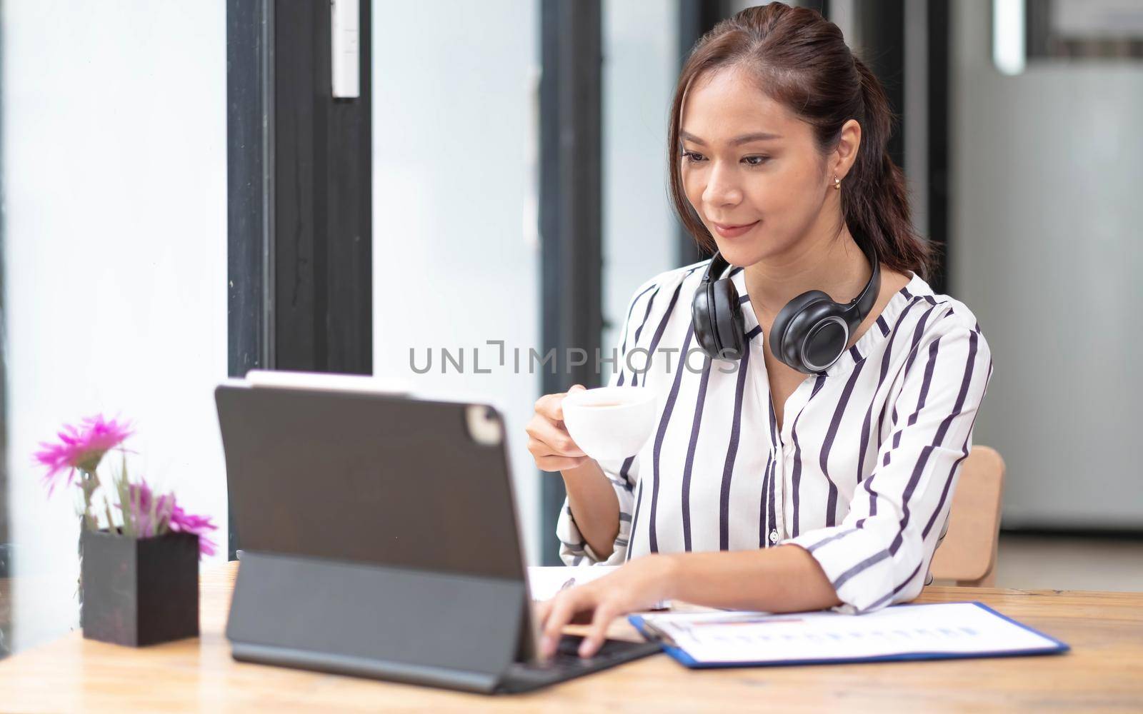 Happy asian woman young wearing headset, communicating with client via video computer call. by wichayada
