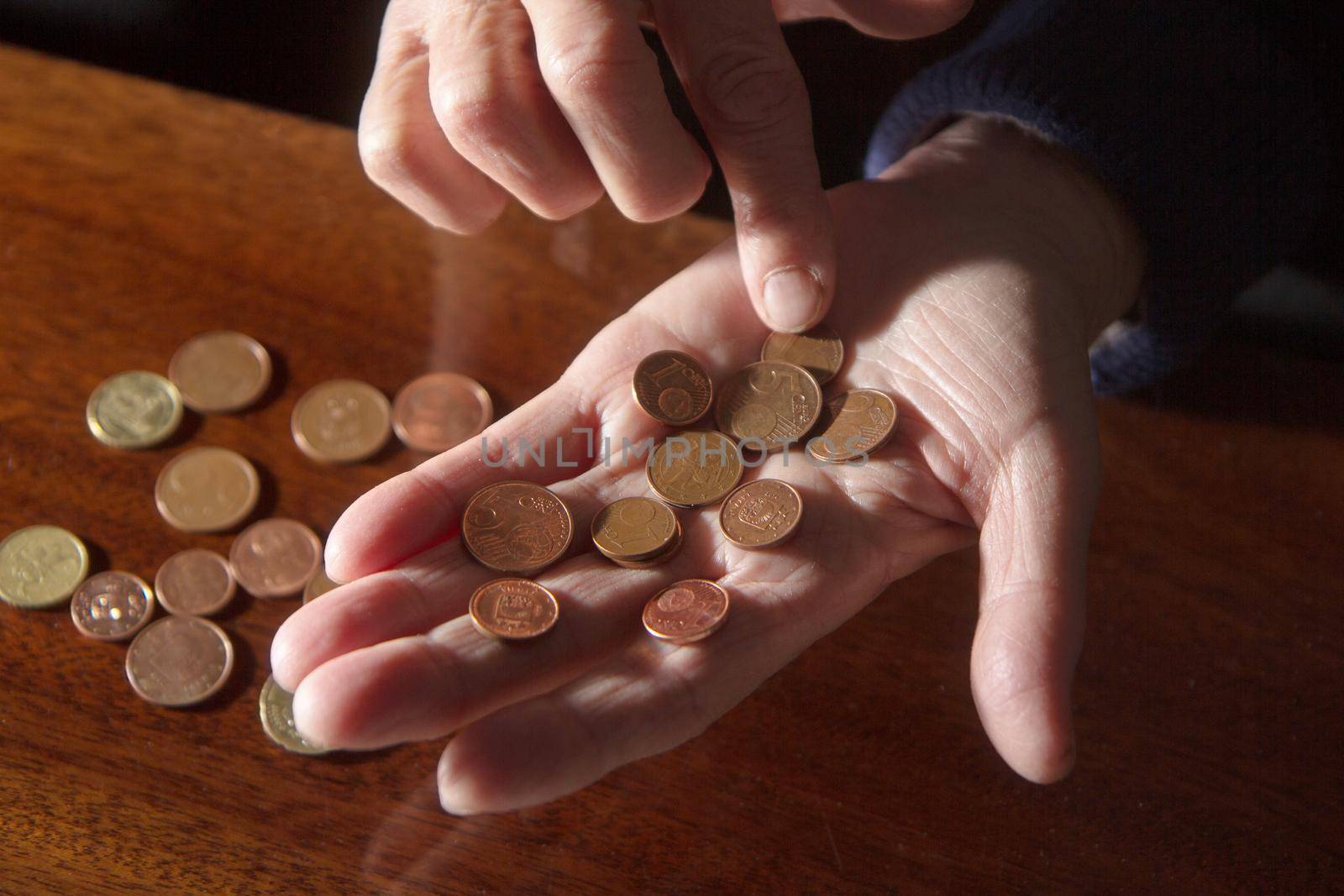 Wrinkled hands of elderly woman counting coins by AigarsR