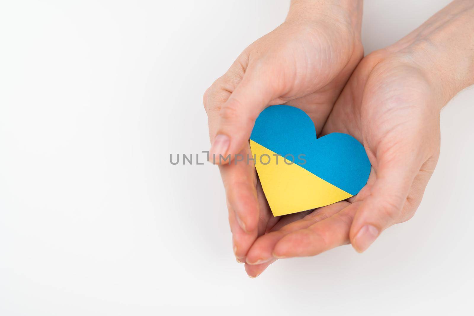 A woman holds a heart with the flag of Ukraine on a white background