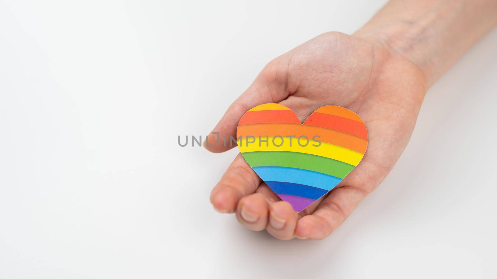 Female hands with rainbow paper heart isolated on white background. Copy space