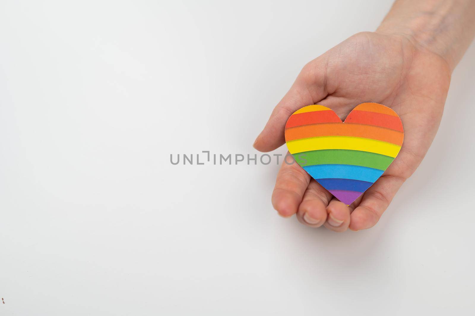 Female hands with rainbow paper heart isolated on white background. Copy space