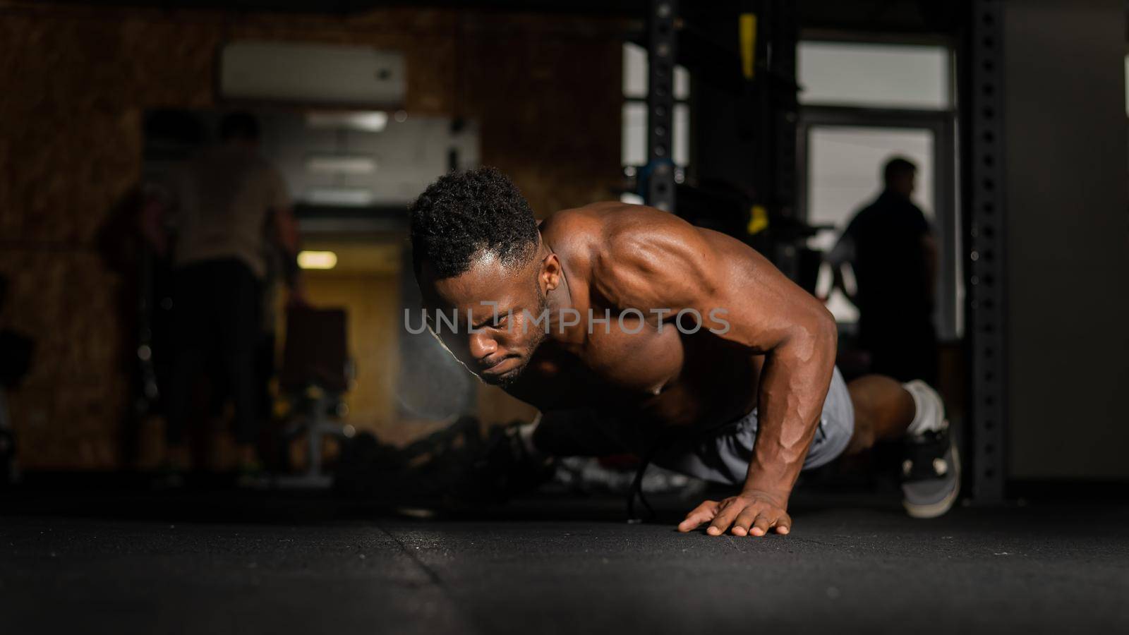 African american man doing one arm push ups in the gym