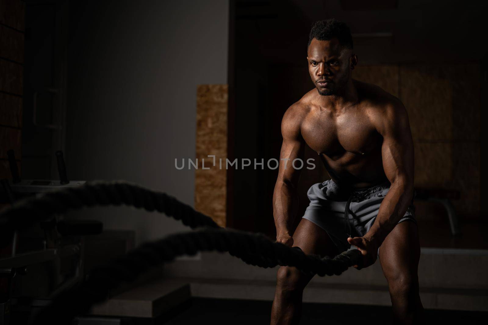 Attractive african american man with naked torso doing endurance exercises with trope