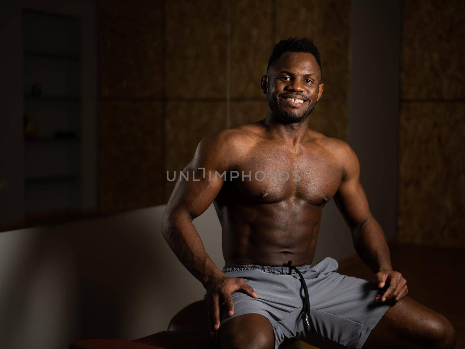 Handsome afro american shirtless man posing in the gym