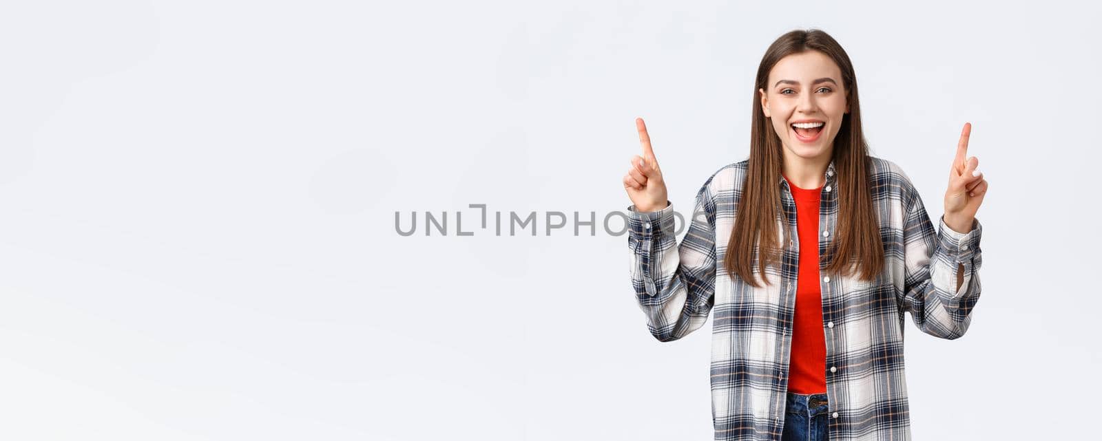 Lifestyle, different emotions, leisure activities concept. Happy beautiful girl in checked shirt, pointing fingers up and laughing carefree, showing good summer vacation ideas, promo or banner by Benzoix