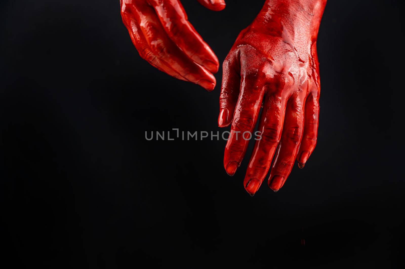 Women's hands in blood on a black background