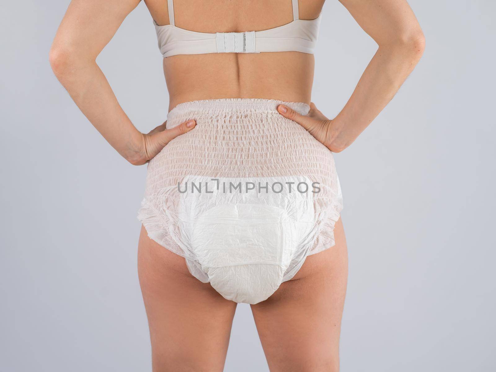 Rear view of a Woman in adult diapers on a white background. Incontinence problem. by mrwed54