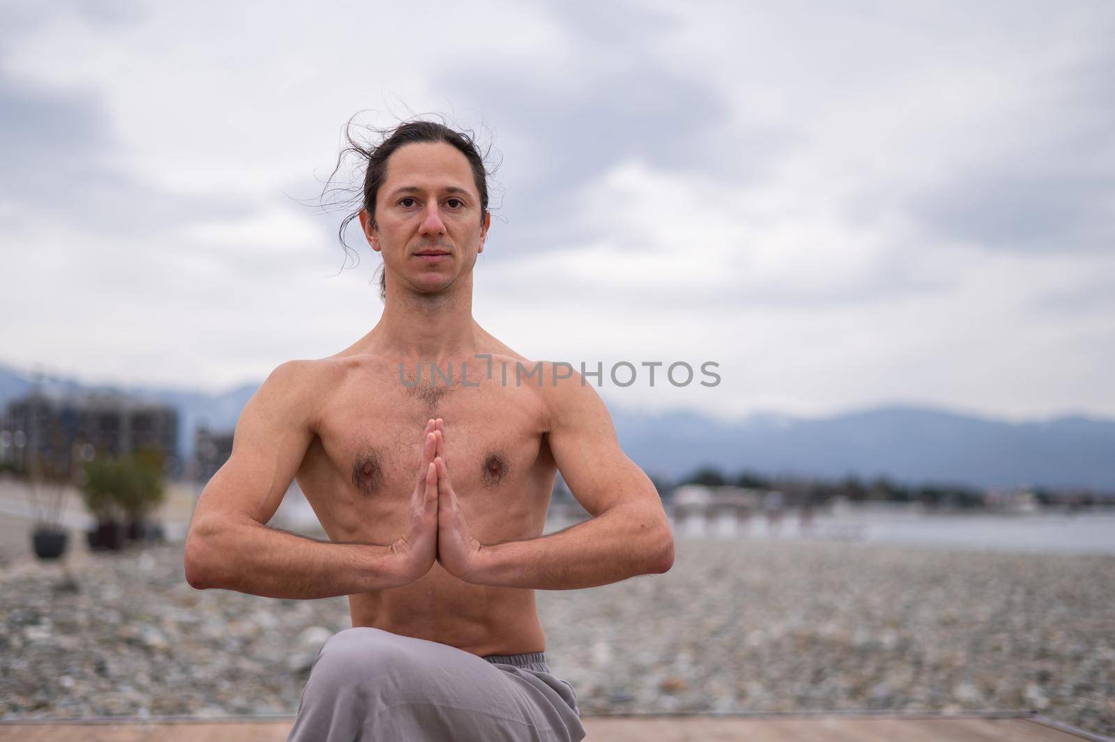 Caucasian man with naked torso practicing wushu on the seashore